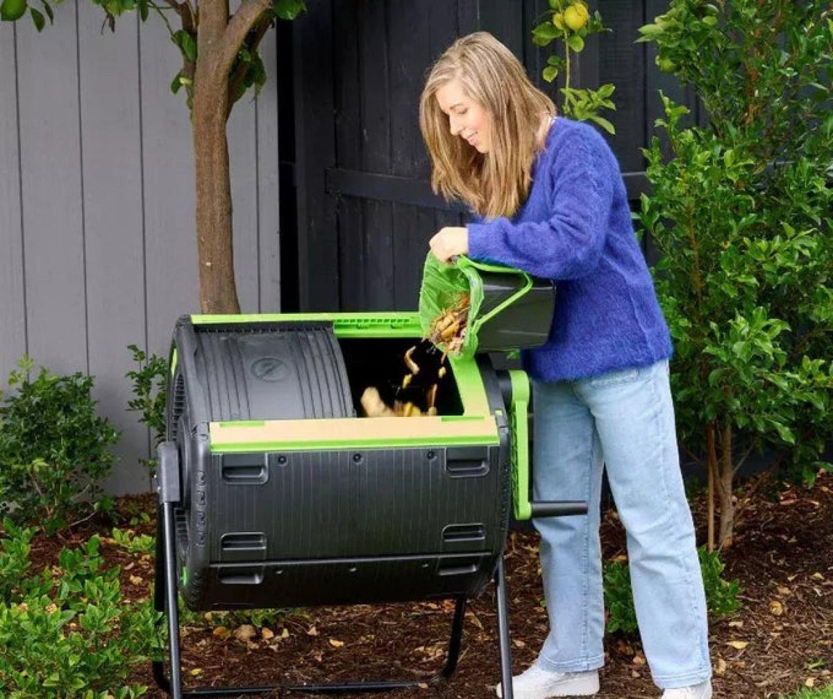 Adding kitchen scraps to compost tumbler