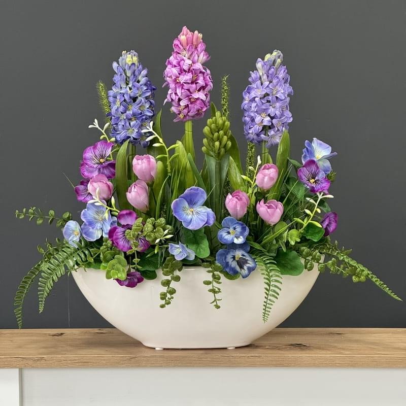 Pink tulips purple hyacinths and yellow-purple pansies in a spring container