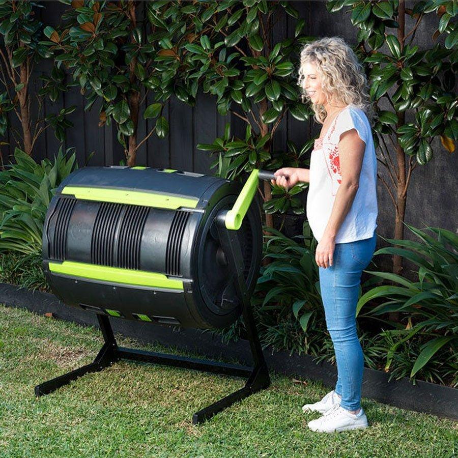 Gardener turning compost tumbler outdoors